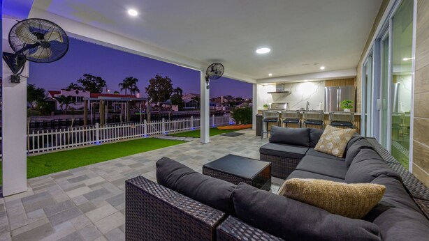 A covered outdoor seating area with a sofa, chairs, and a fan. - Waterfront Heated Pool Home Gym Fire Pit (Tampa)