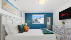 A bedroom with a bed, pillows, a window, a dresser, and a TV displaying 'NETFLIX'. - Waterfront Heated Pool Home Gym Fire Pit (Tampa)