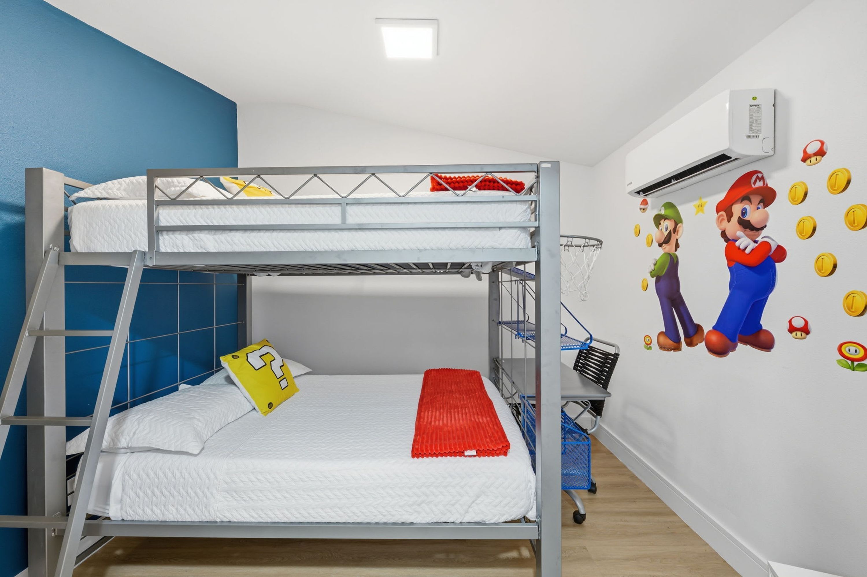 A bunk bed with a ladder, a small table, and a wall with Mario and Luigi wall decals.