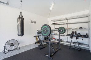 A gym with a punching bag, weightlifting equipment, and a fan. - Waterfront Heated Pool Home Gym Fire Pit (Tampa)