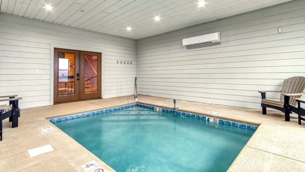Una piscina con borde de azulejos, un banco y una silla.