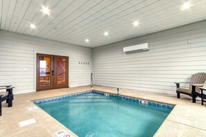 A swimming pool with a tiled edge, a bench, and a chair. - Sweet Mimosa Lodge Indoor Pool Hot Tub Views (Sevierville)
