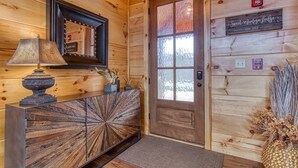 Interior de madera con una puerta, un espejo, una lámpara y un adorno en la pared.