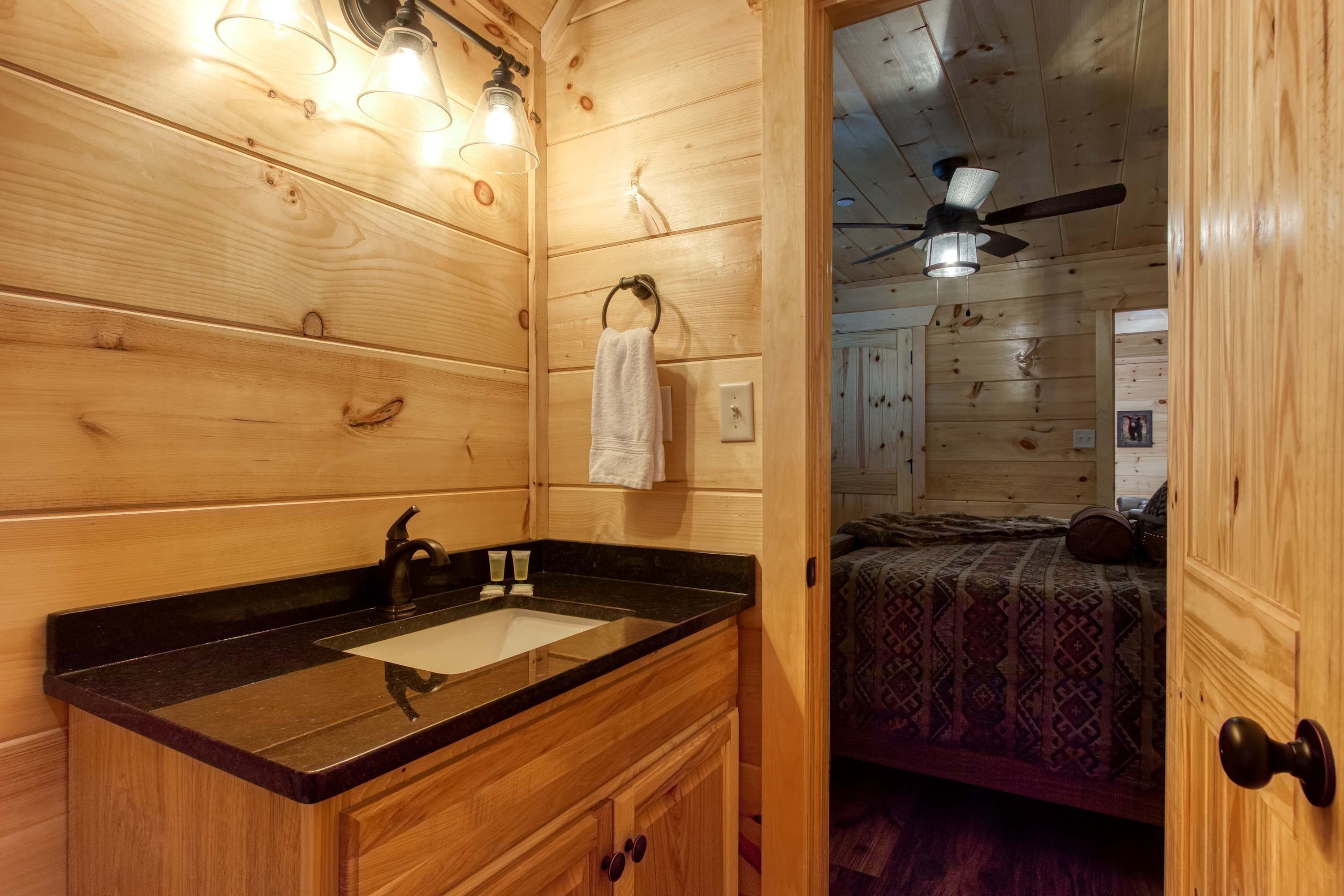 A wooden cabin interior with a bathroom featuring a sink, vanity, and towel rack.