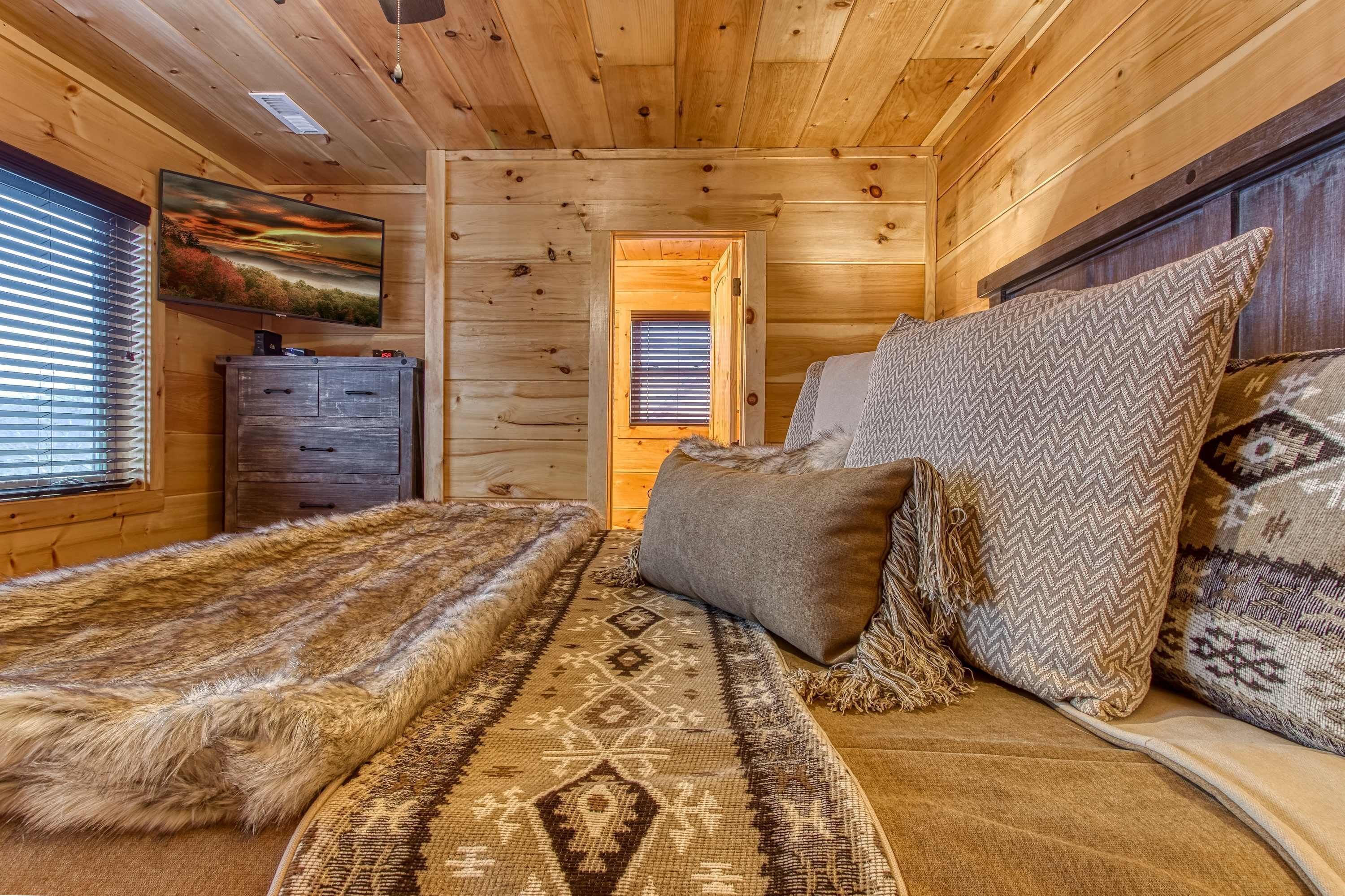 Ein gemütliches Zimmer mit einem Bett, Kissen, einem Teppich, einem Schminktisch und einem Bild an der Wand.