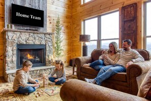 A cozy living room with a stone fireplace, a television, and a large window. - Sweet Mimosa Lodge Indoor Pool Hot Tub Views (Sevierville)