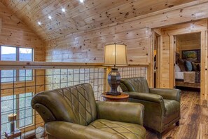 A cozy cabin interior with wooden walls, a window with a view, and a seating area with a lamp. - Sweet Mimosa Lodge Indoor Pool Hot Tub Views (Sevierville)