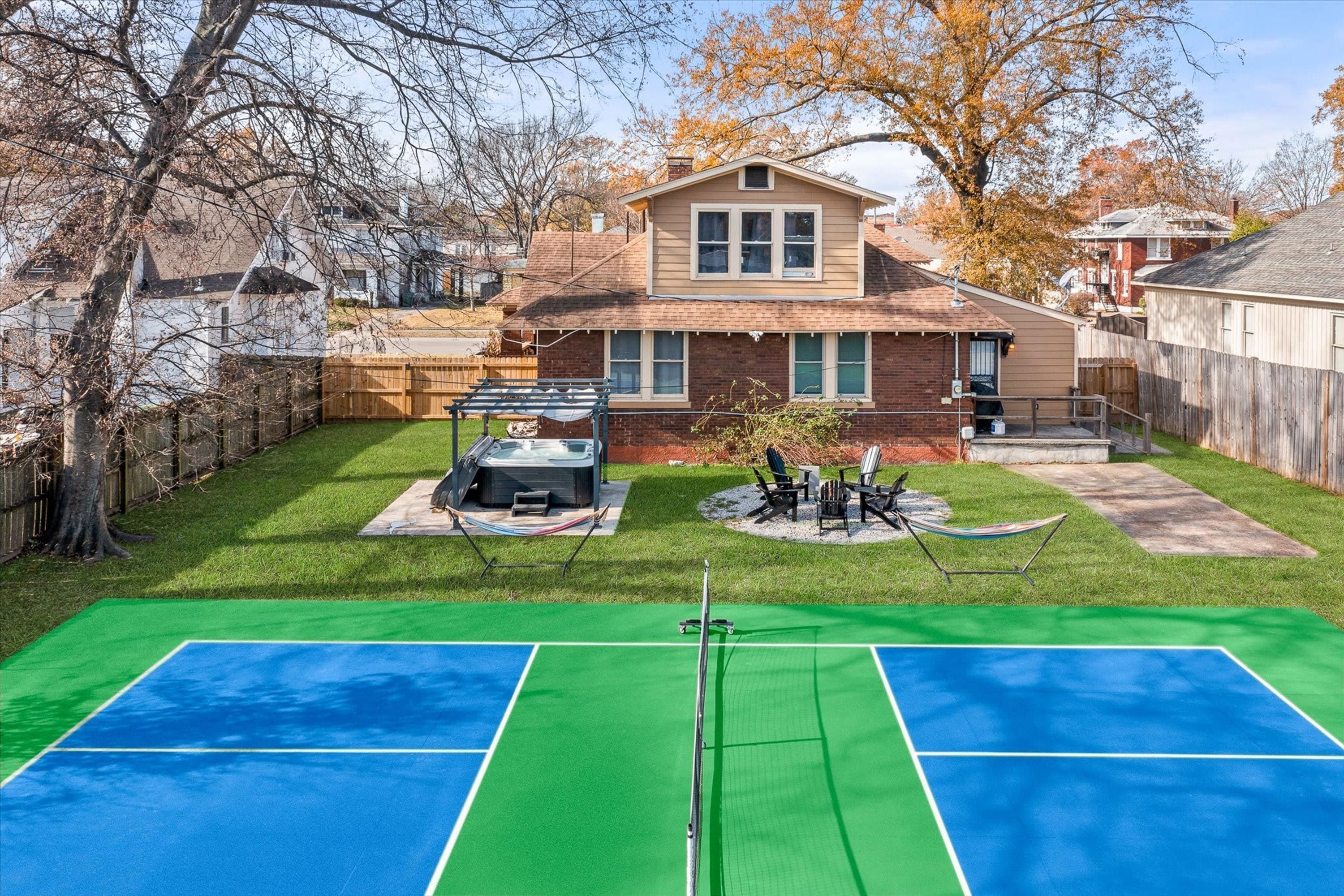 Ein Garten mit Tennisplatz, Whirlpool und Sitzgelegenheit im Freien.