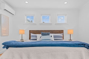 A bedroom with a large bed, two bedside lamps, a wooden headboard, and three windows with blinds. - Downtown Flat Walk to Dining Shops Sleeps 4 (St. Michaels)