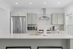 A modern kitchen with stainless steel appliances, a tiled backsplash, and a large window. - Downtown Flat Walk to Dining Shops Sleeps 4 (St. Michaels)