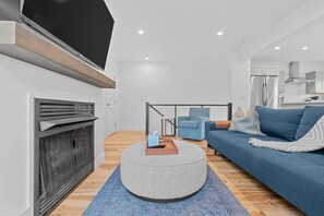 A modern living room with a fireplace, a sofa, a coffee table, and a television mounted on the wall. - Downtown Flat Walk to Dining Shops Sleeps 4 (St. Michaels)