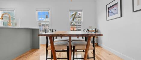 Una cocina moderna con una mesa de comedor de madera, sillas e iluminación colgante.