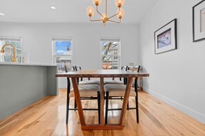 A modern kitchen with a wooden dining table, chairs, and a pendant light. - Downtown Flat Walk to Dining Shops Sleeps 4 (St. Michaels)