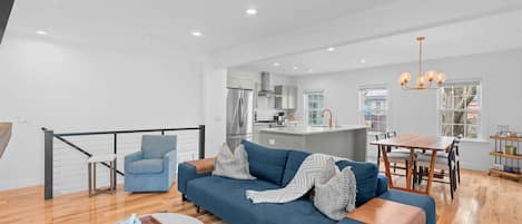 A modern living room with a sofa, a coffee table, and a dining area with a table and chairs.