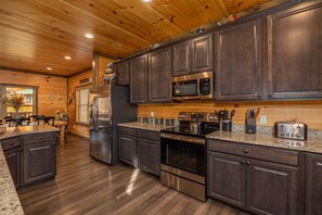 A modern kitchen with dark wood cabinets, stainless steel appliances, and a granite countertop.