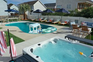 A backyard with a swimming pool, lounge chairs, a hot tub, and umbrellas. - Myrtle Beach Compound Golf Sim Pool Spa Sleeps 28 (North Myrtle Beach)