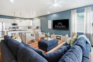 Ein modernes Wohnzimmer mit einem großen, blauen Sofa, einem Couchtisch und einem an der Wand befestigten Fernseher.