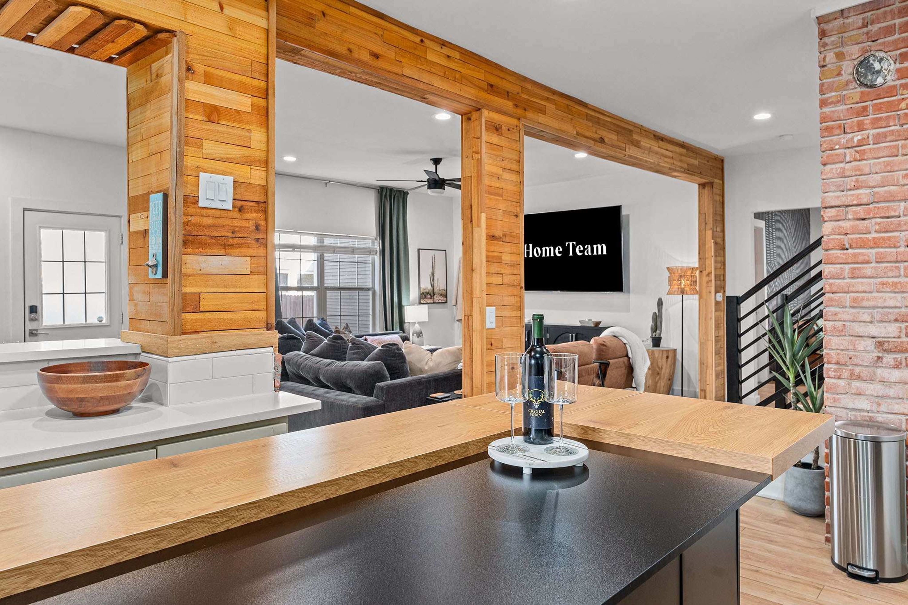 A modern kitchen with a wooden countertop, a dining area with a couch, and a living room with a TV.