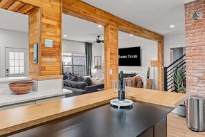 A modern kitchen with a wooden countertop, a dining area with a couch, and a living room with a TV. - Sleeps 16 - Roof Top - Game Room - Pet Friendly (Oklahoma City)
