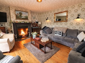 Una sala de estar acogedora con chimenea, un sofá, una mesa de centro y un televisor.