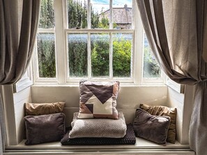 A window seat with cushions and a view of greenery outside. - Prudhoe Cottage (Prudhoe)