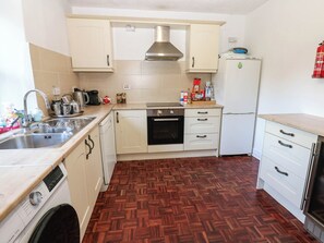 A compact kitchen with a washing machine, a stove, and a refrigerator. - Prudhoe Cottage (Prudhoe)