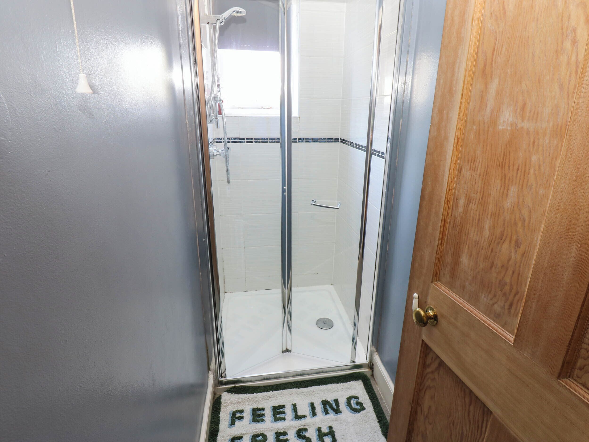 Une salle de bain avec une douche, un porte-serviettes et une porte dotée d’une poignée.
