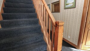 A staircase with a wooden handrail and carpeted steps. - Prudhoe Cottage (Prudhoe)