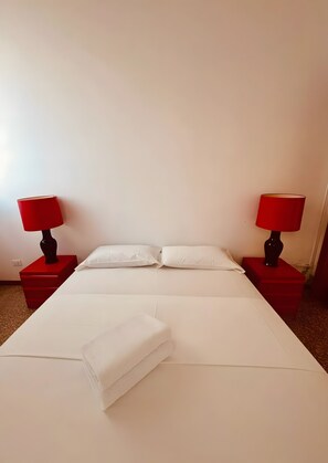 Ein Hotelzimmer mit einem großen Bett, zwei roten Nachttischen und passenden roten Lampen.