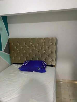A bed with a tufted headboard, a white mattress, and a blue pillow. - Hotel Linkon Riohacha (Riohacha)