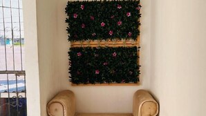 Un rincón con un sofá color beige y una planta de pared con follaje verde y flores rosadas.