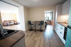 Une cuisine moderne avec un coin repas, un plancher en bois et une vue sur le salon.
