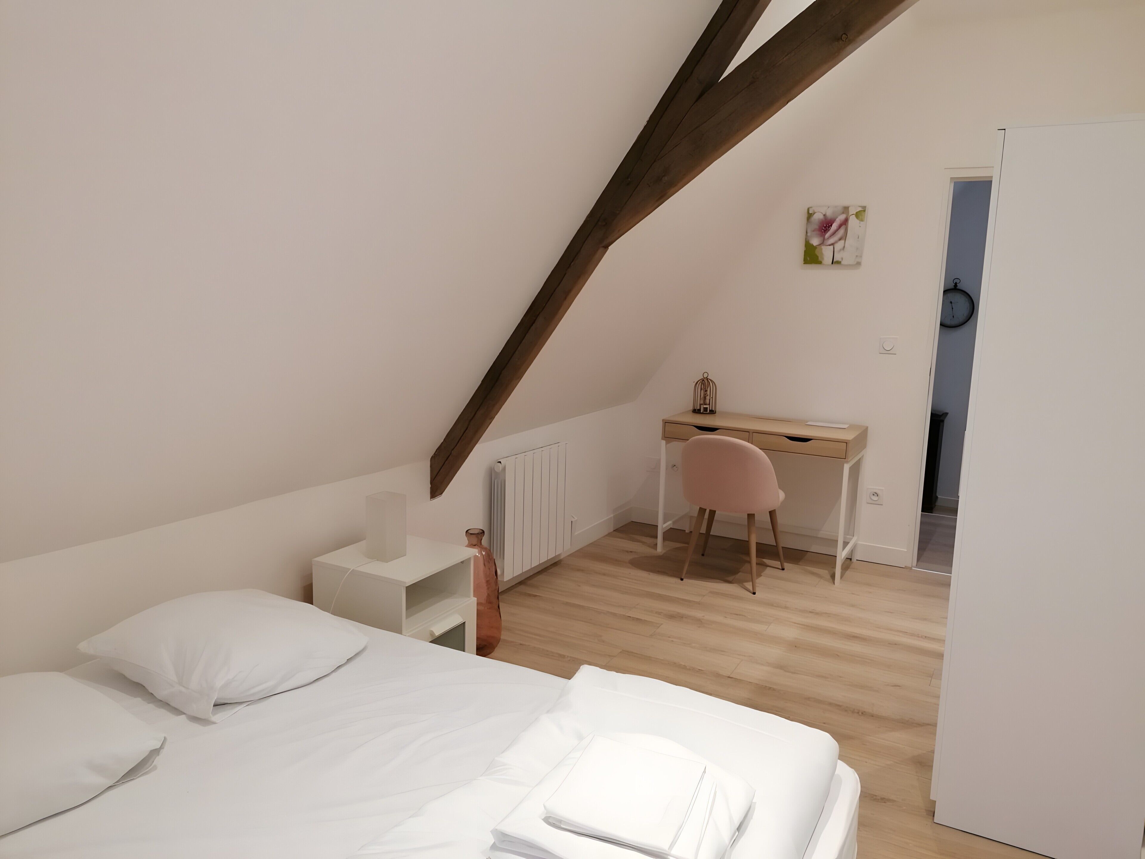 A bedroom with a bed, a desk, and a chair.