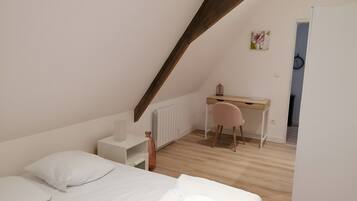 A bedroom with a bed, a desk, and a chair.