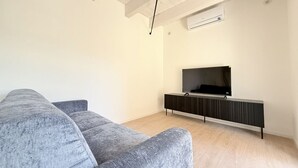 Ein modernes Wohnzimmer mit einem grauen Sofa, einer schwarzen Unterhaltungseinheit und einem Wand-Fernseher.
