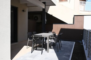 An outdoor patio with a table and chairs, a covered area, and a building entrance. - SE310 – Senigallia, stylish apartment with air conditioning, private garage and outdoor courtyard (Senigallia)