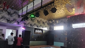 A room with a marble wall, a stage with lighting equipment, and a seating area. - The Art of Field (Udaipur)