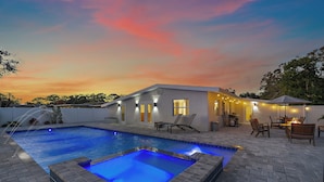 A swimming pool with a hot tub, outdoor seating, and a building with string lights. - Memory‑Making Sarasota Stay with Heated Pool, Spa & Modern Comfort (Sarasota)