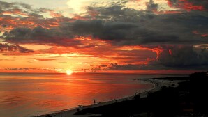 A beach scene with a sunset over the ocean, people on the shore, and a distant shoreline. - Memory‑Making Sarasota Stay with Heated Pool, Spa & Modern Comfort (Sarasota)