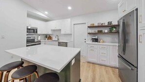 A modern kitchen with white cabinetry, a large island, and stainless steel appliances. - Memory‑Making Sarasota Stay with Heated Pool, Spa & Modern Comfort (Sarasota)