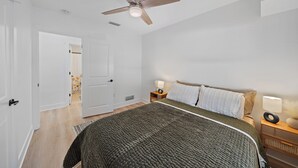 A bedroom with a bed, a ceiling fan, a nightstand with a lamp, and a door leading to another room. - Memory‑Making Sarasota Stay with Heated Pool, Spa & Modern Comfort (Sarasota)