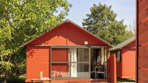 A red wooden cabin with a porch, a table, and a guitar. - Family Cottage (Saint-Thibault-des-Vignes)