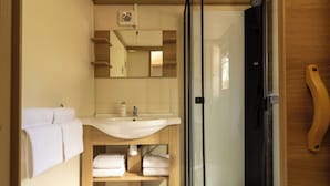 A compact bathroom with a sink, mirror, and a glass shower enclosure. - Family Cottage (Saint-Thibault-des-Vignes)