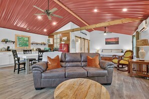 A spacious living area with a leather sofa, a round coffee table, and a dining area with a wooden table and chairs.