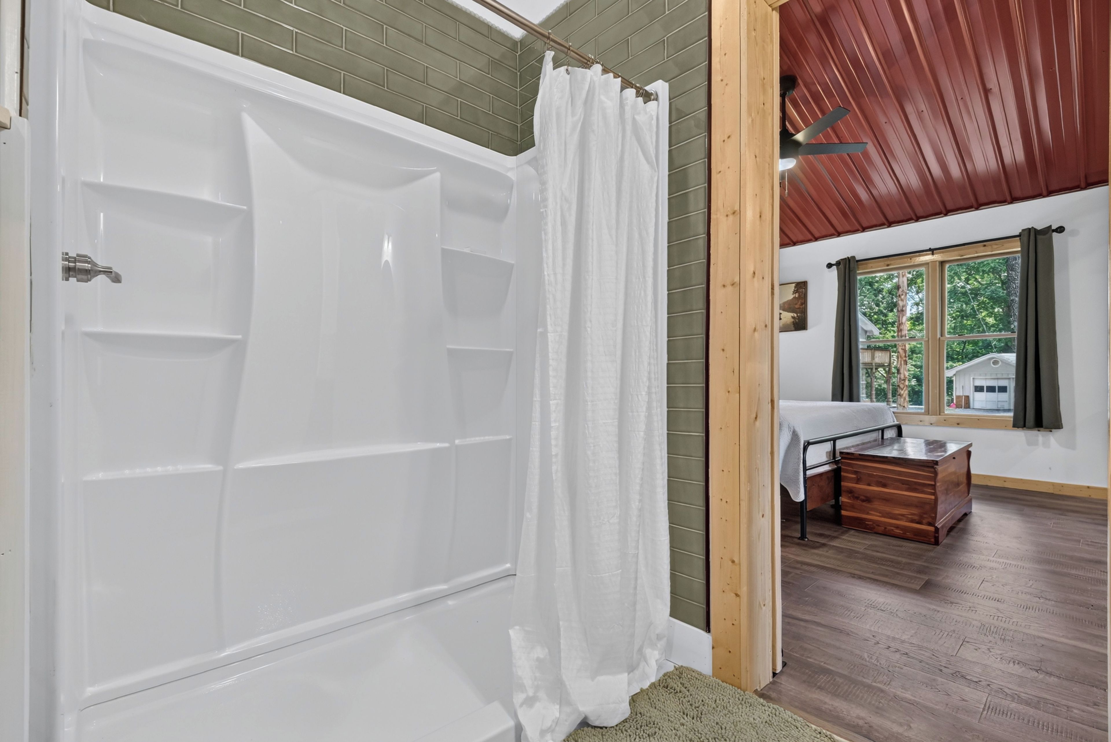 A bathroom with a white bathtub, a shower curtain, and a wooden floor.