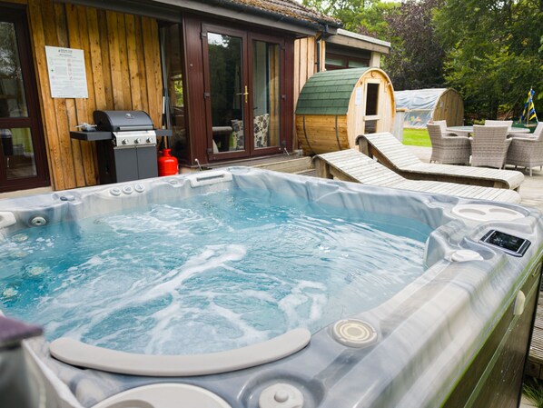 A hot tub with a wooden deck and lounge chairs. - Kinloch Lodge - Highland hot tub lodge close to Loch Ness (Drumnadrochit)