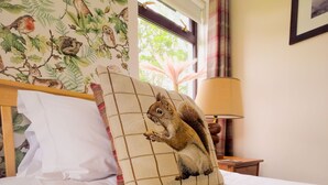 A bed with a white pillow and a decorative pillow featuring a squirrel. - Kinloch Lodge - Highland hot tub lodge close to Loch Ness (Drumnadrochit)