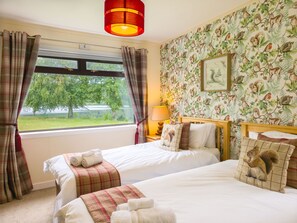 A room with two beds, a window with curtains, a lamp, and a wall with a nature-themed wallpaper. - Kinloch Lodge - Highland hot tub lodge close to Loch Ness (Drumnadrochit)