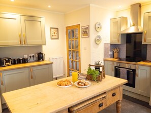 A modern kitchen with wooden cabinets, a countertop with breakfast items, and a built-in oven. - Kinloch Lodge - Highland hot tub lodge close to Loch Ness (Drumnadrochit)