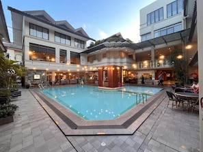 Ein Innenpool mit einer Holzterrasse, umgeben von Gebäuden mit Balkonen und Außenbereichen zum Sitzen.